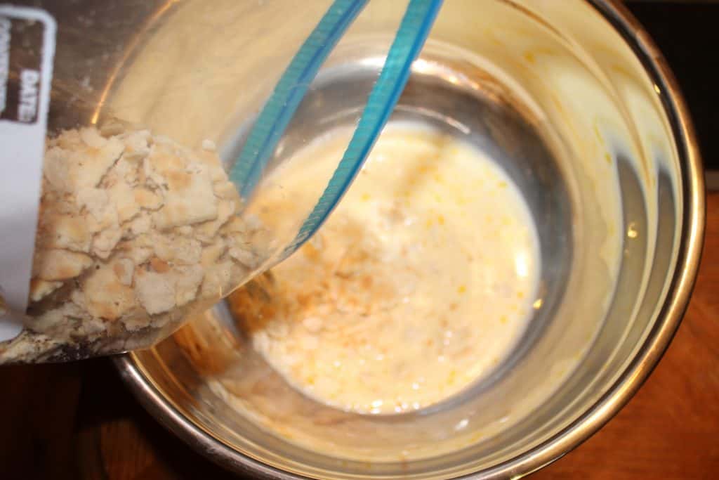 adding crushed saltine crackers to the milk and egg mixture