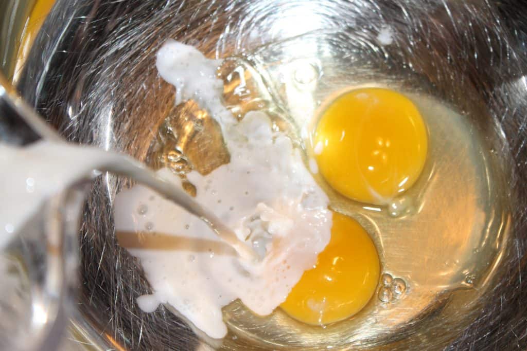 adding milk and eggs to a large mixing bowl