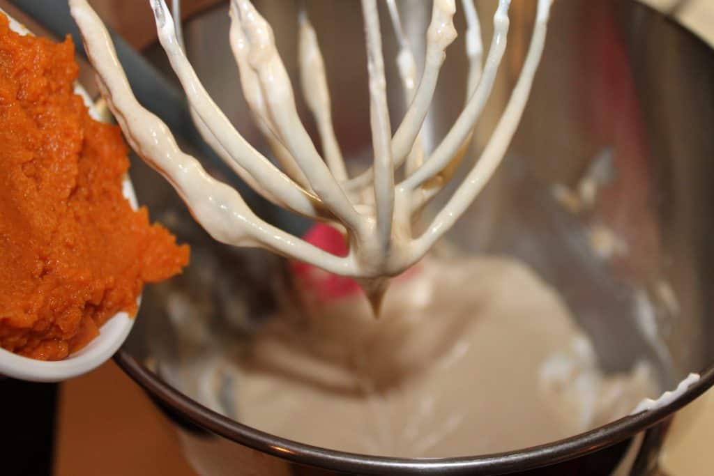 adding pumpkin puree to the mixing bowl