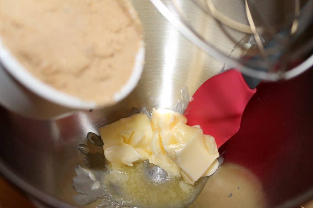 adding butter and brown sugar to a mixing bowl