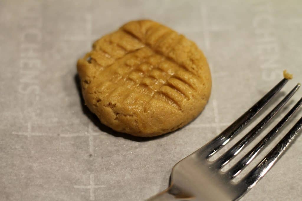 Uncooked peanut butter cookie flattened with fork tines.