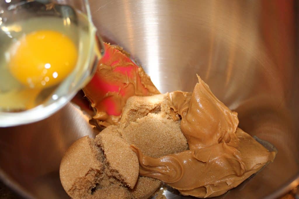 Adding egg, peanut butter, and brown sugar to a mixing bowl.