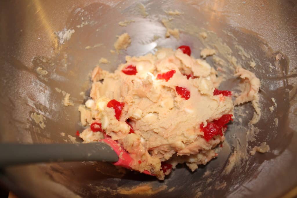 adding the maraschino cherries to the cookie dough using a rubber spatula