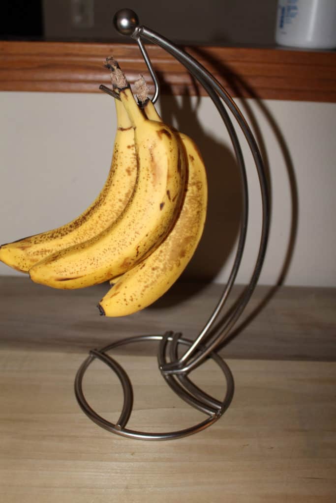 Bananas starting to turn brown hanging on a banana holder 