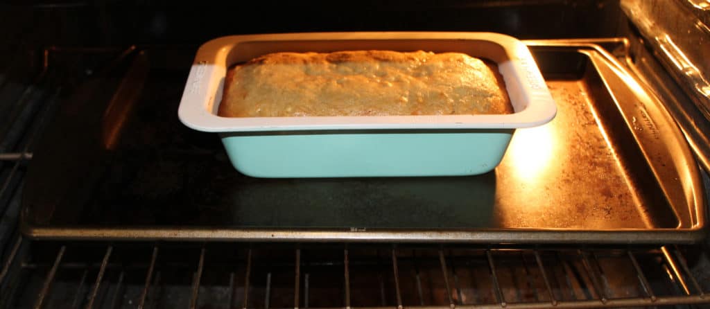 Pineapple Banana Bread in a loaf pan on a cookie sheet in the oven