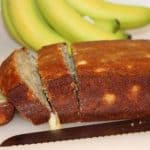 pineapple banana bread sliced on a cutting board with bananas behind the bread