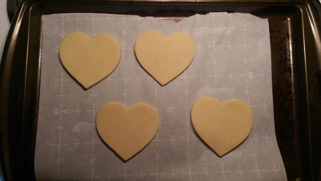 heart shaped sugar cookies that are on a cookie sheet lined with parchment paper