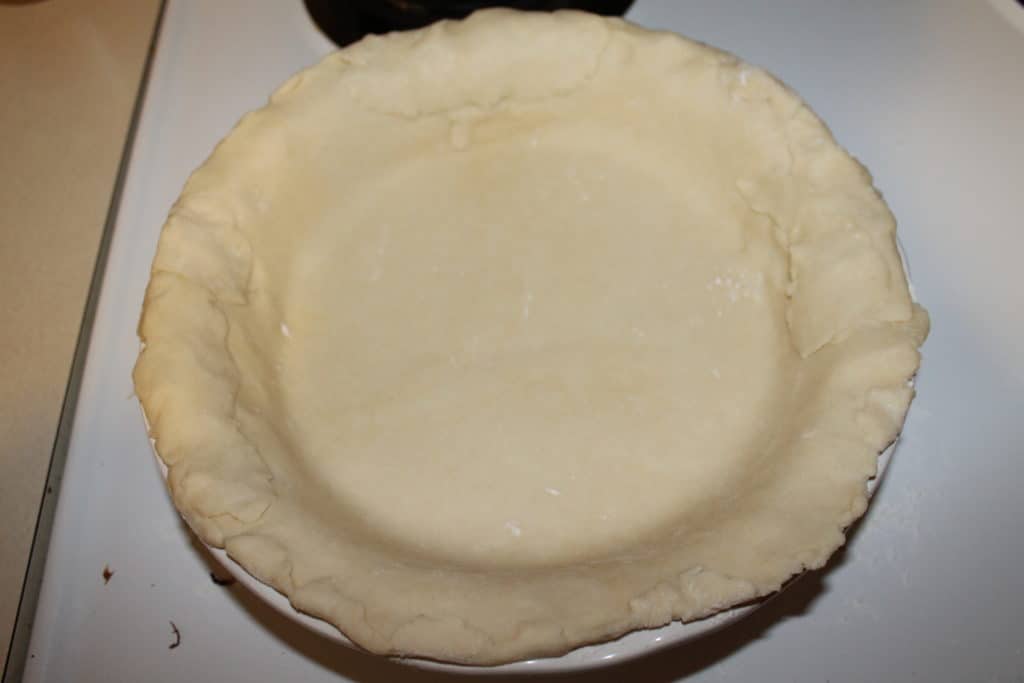 the unfolded pie dough evenly placed into the ceramic pie dish