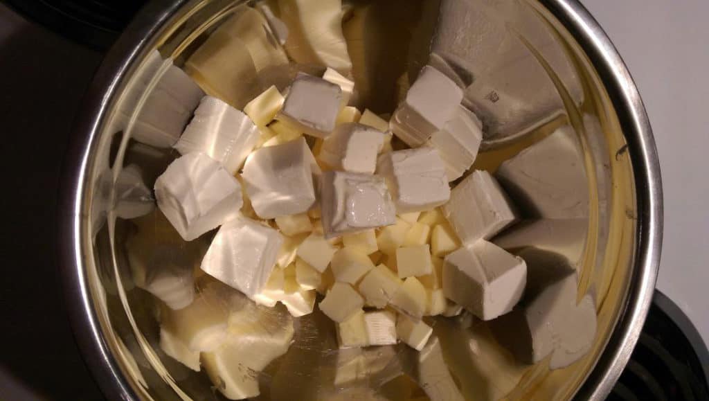 a mixing bowl with cubed butter and cubed cream cheese