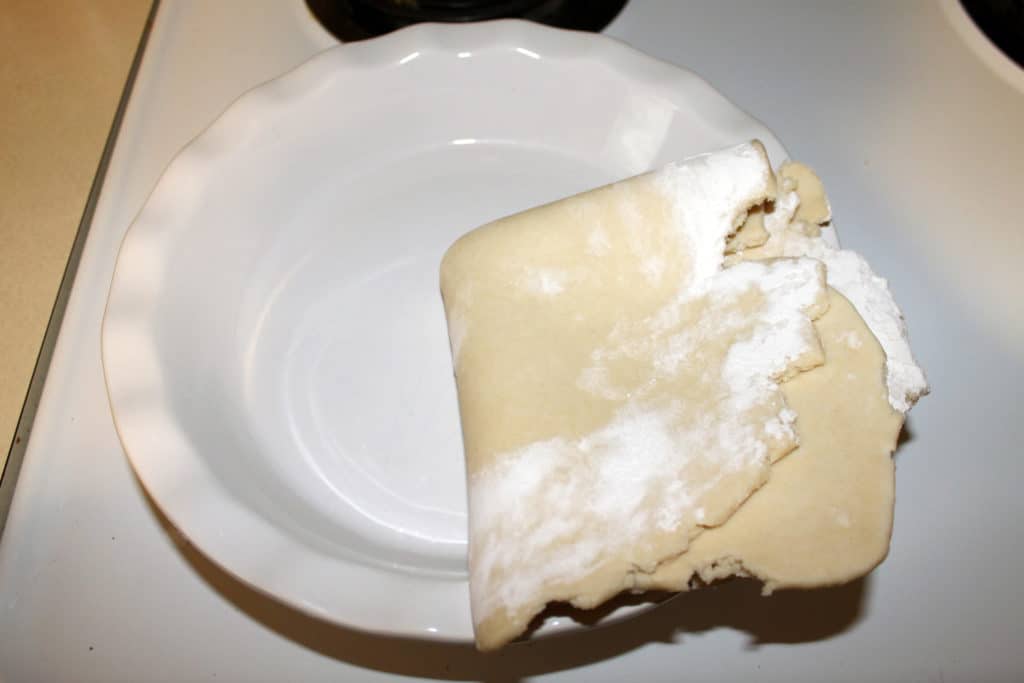 the pie dough folded in half then half again and placed into a pie dish