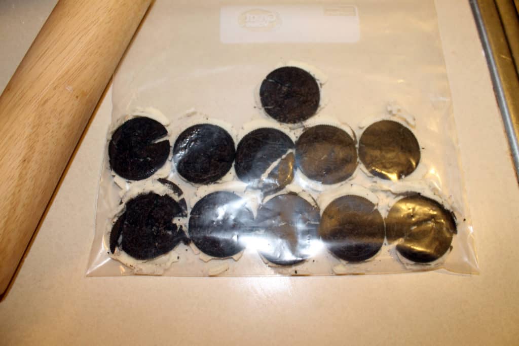 Smashed up oreos in a large ziploc bag with a rolling pin beside it.