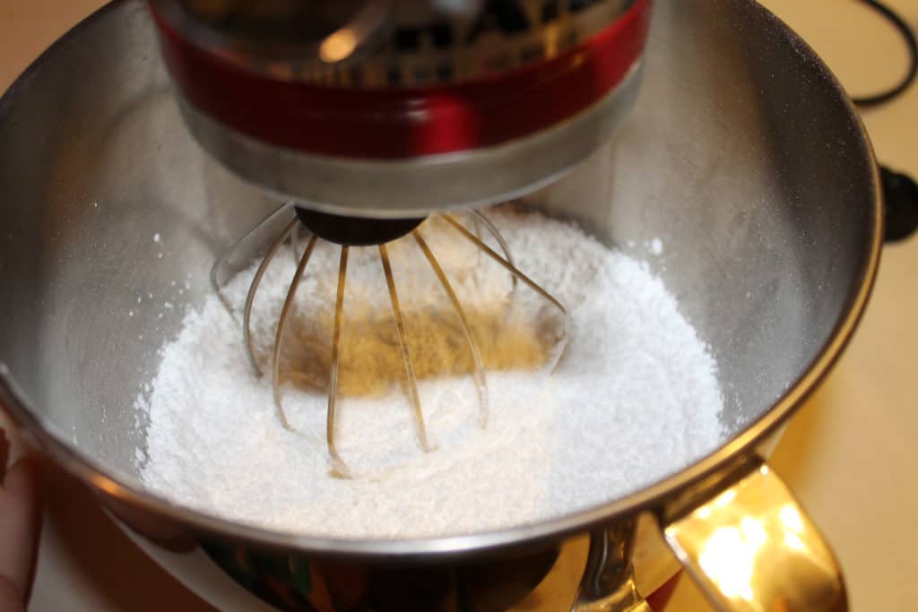 Powdered sugar added to a mixing bowl with a whisk attachment