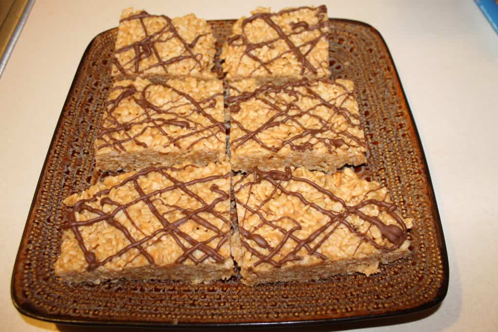 6 large rice crispy treats with peanut butter on a brown plate.