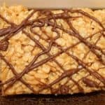 One peanut butter rice crispy treat stood up to show detail on a brown plate.