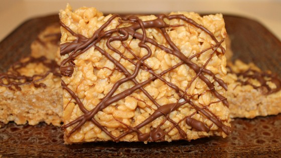 One peanut butter rice crispy treat stood up to show detail on a brown plate.