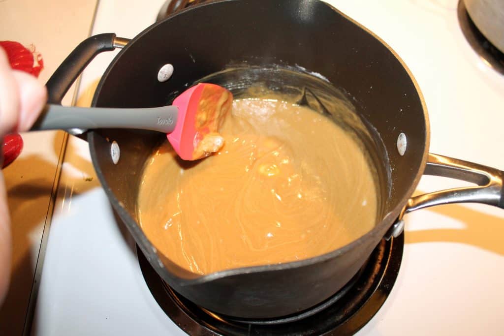 Melted peanut butter, butter, powdered sugar, and milk in a saucepan.