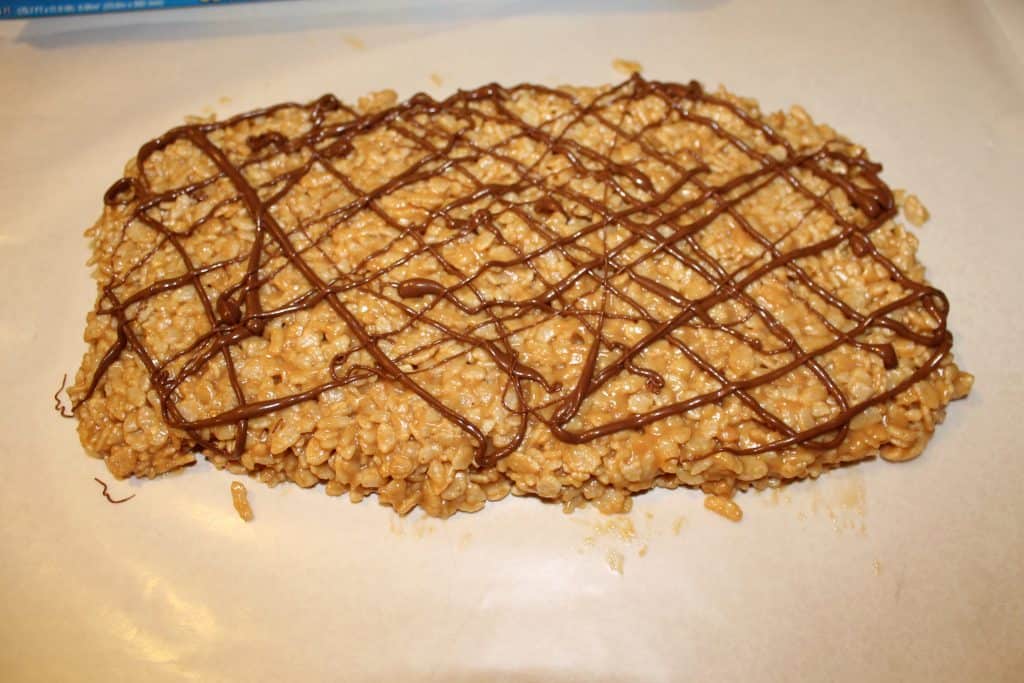 Chocolate drizzled over the top of peanut butter rice crispy treats.