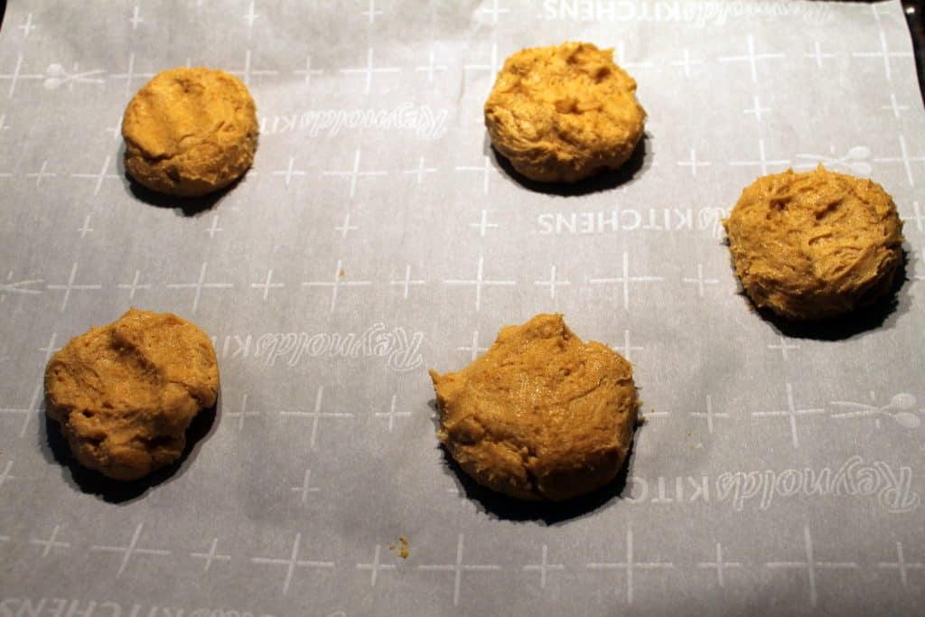 Un-baked pumpkin cookies on a cookie sheet.