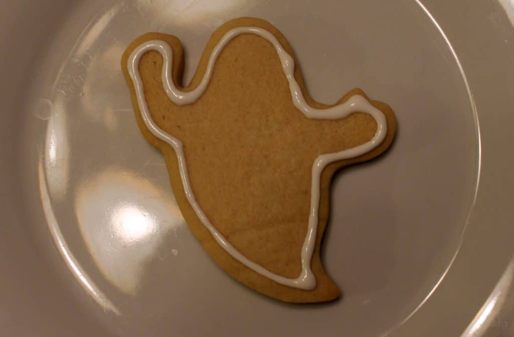 Ghost sugar cookie outlined in white royal icing. 