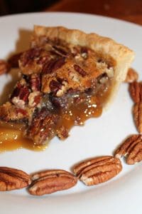 a slice of delicious pecan pie with a buch of pecans circling the slice. 