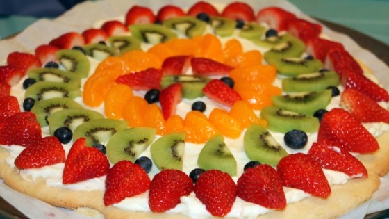 close up image of a fruit pizza topped with strawberries, blueberries, kiwi, and oranges