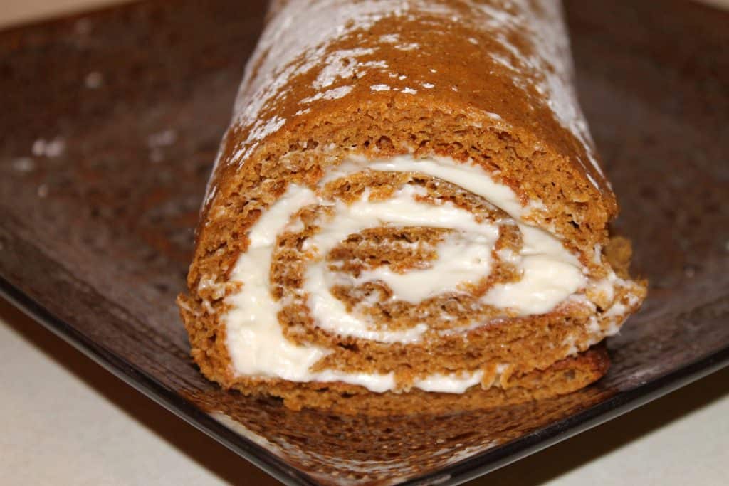 close up image of a pumpkin roll on a brown serving plate