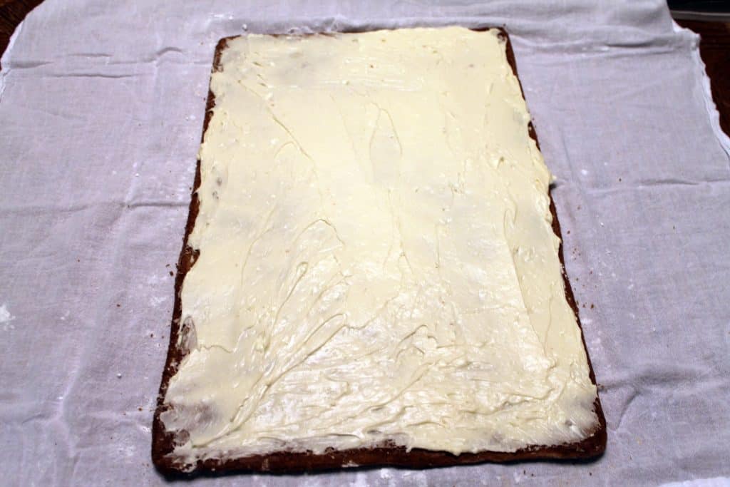 unroll pumpkin cake and spread the cream cheese icing evenly over the entire cake.