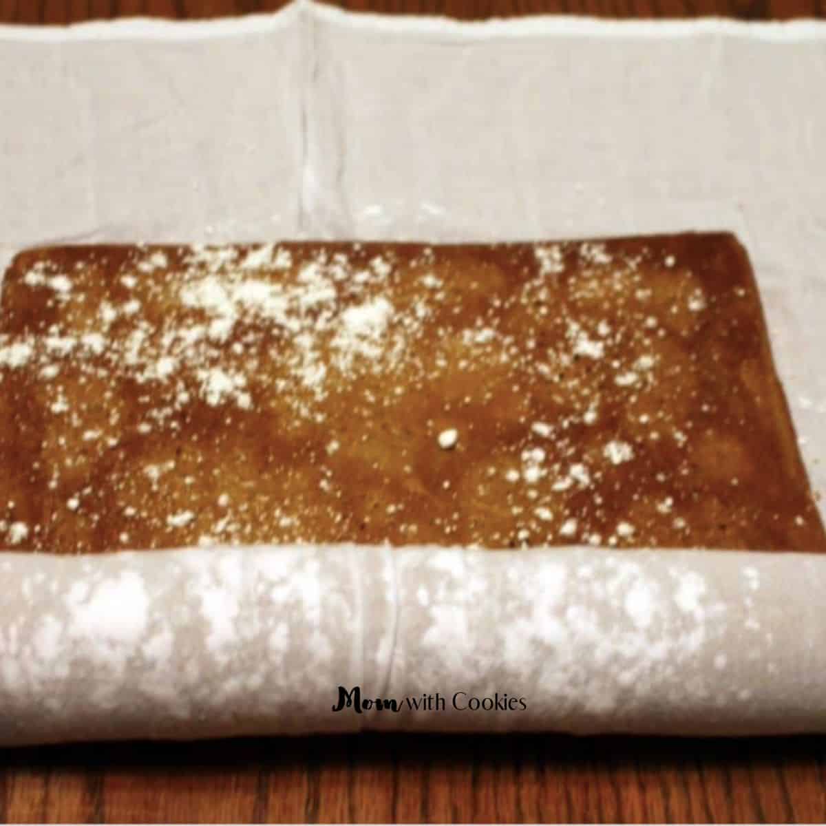a pumpkin cake being rolled in a cheesecloth with powdered sugar