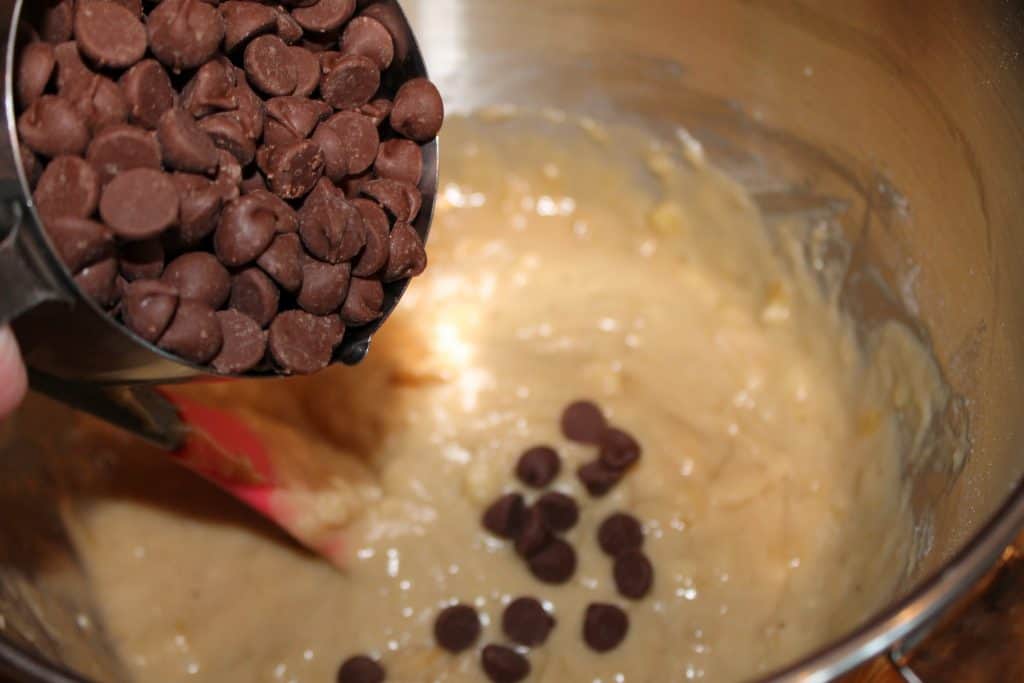 adding chocolate chips to the mixing bowl