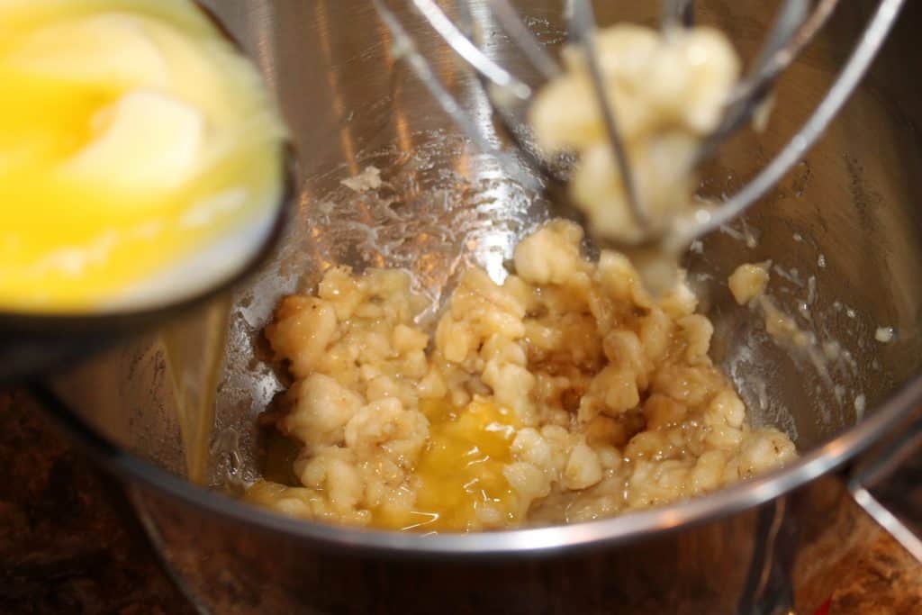 adding bananas and melted butter to a mixing bowl