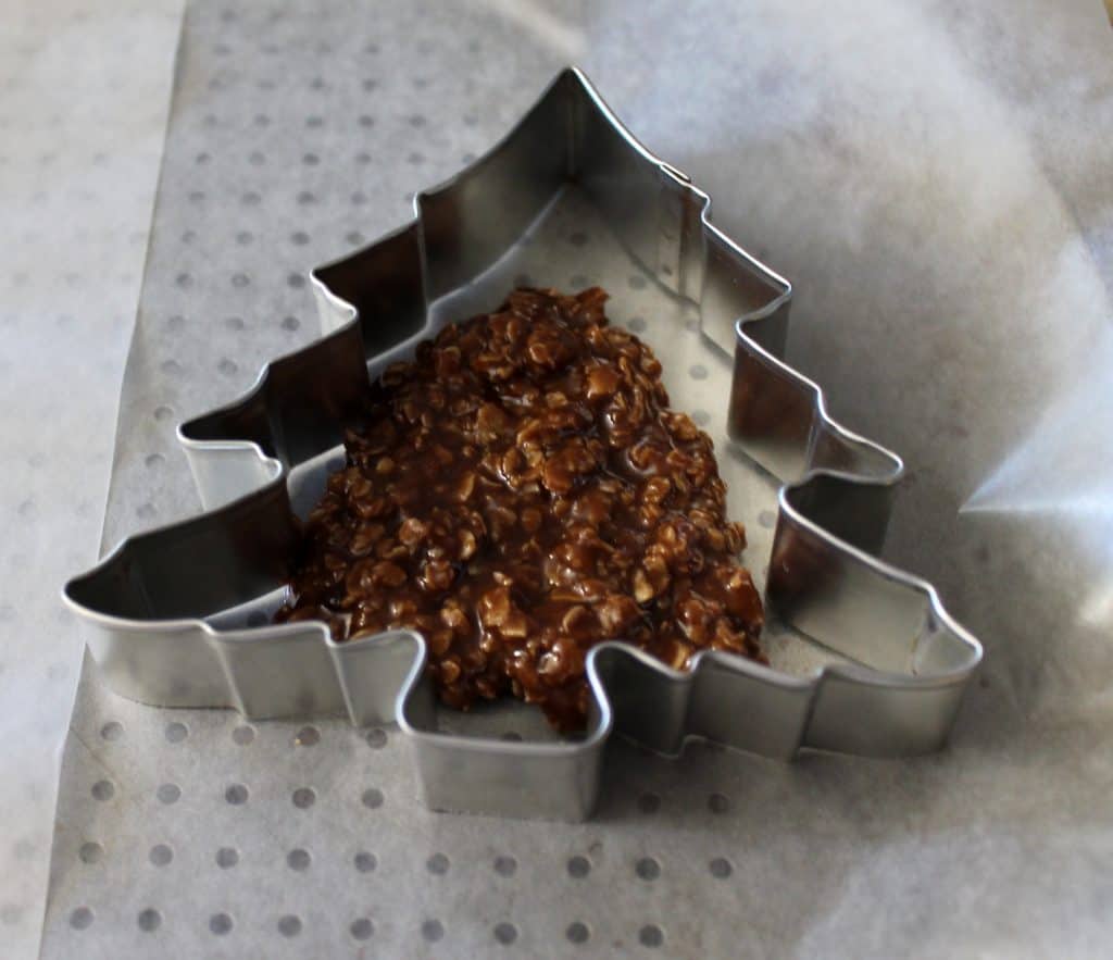 putting warm no bake cookie dough into a tree shaped cookie cutter