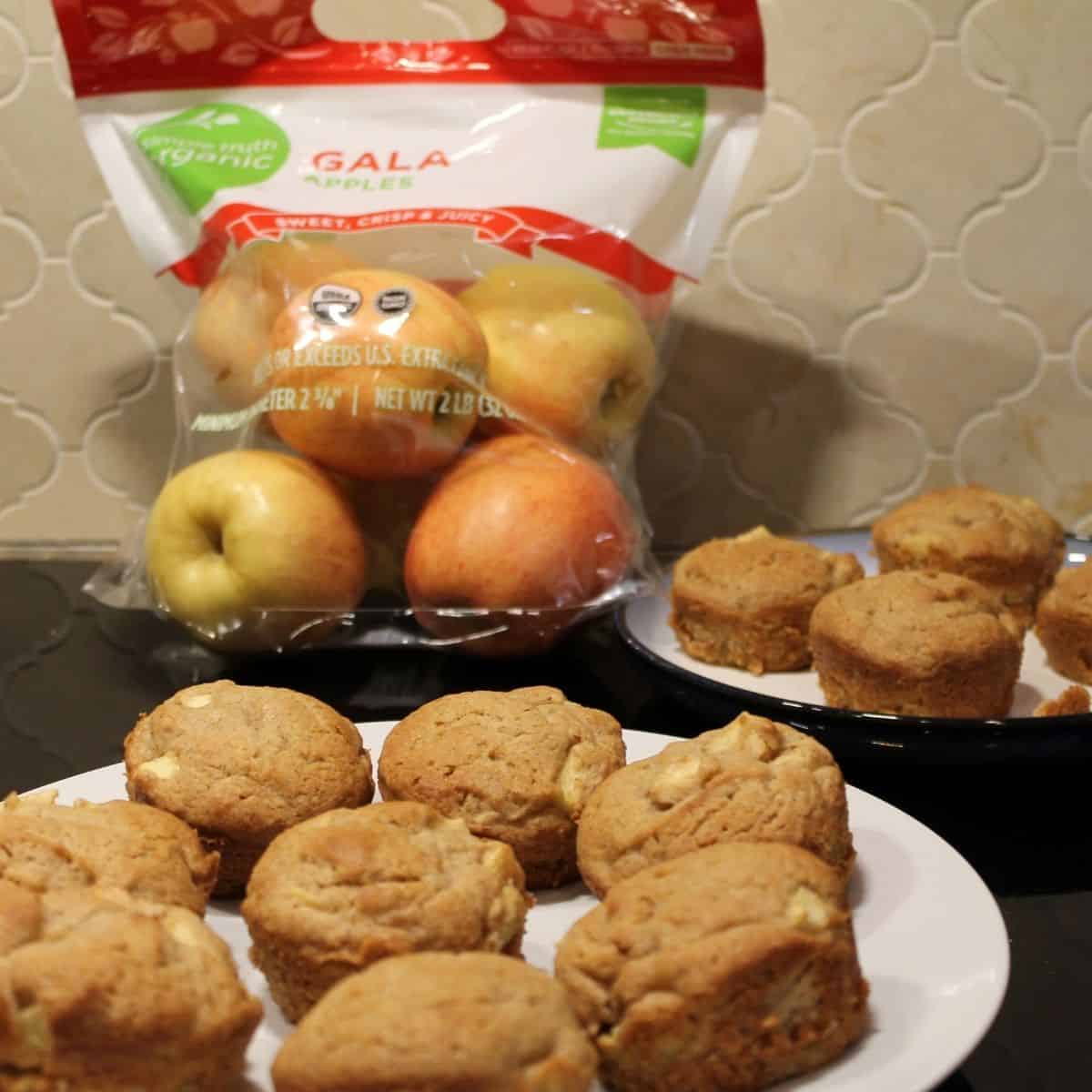 homemade apple cinnamon muffins on a plate near a bag of gala apples