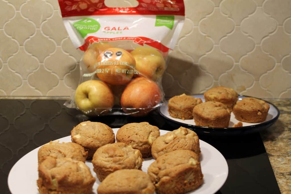 a bunch of apple cinnamon muffins on plates with a bag of gala apples nearby