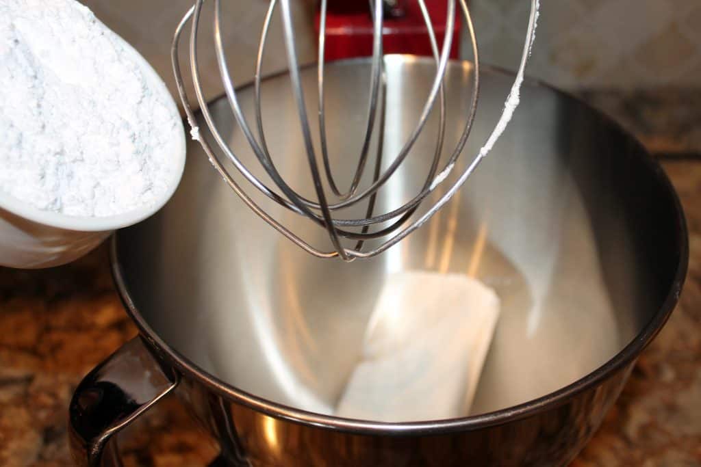 adding powdered sugar and cream cheese to a mixing bowl