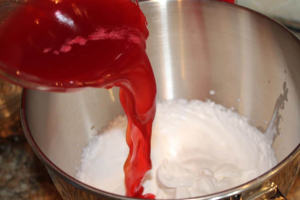 Adding raspberry gelatin to the whipped cream.