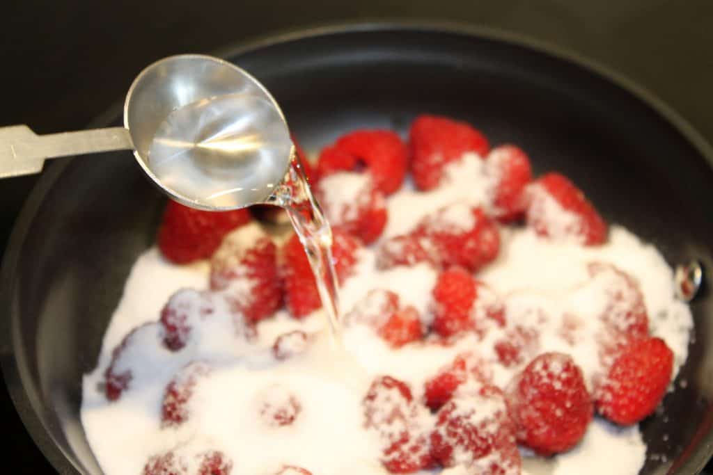 Adding water to frying pan with raspberries and sugar.