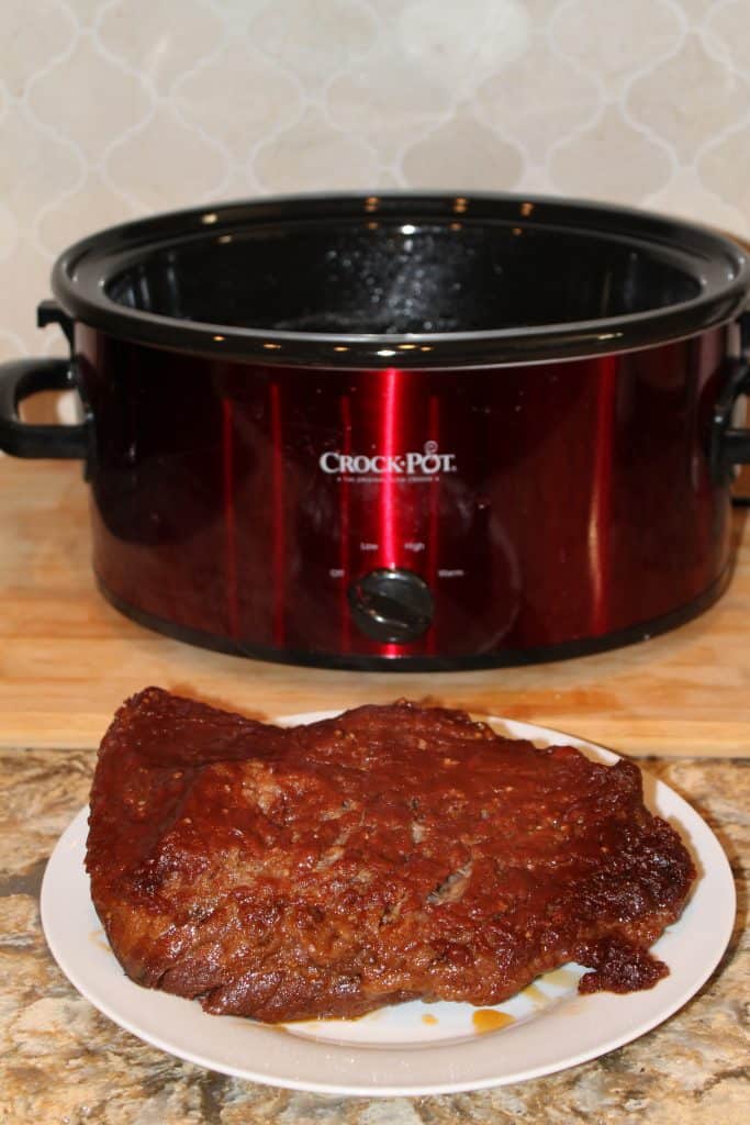 Finished BBQ brisket in front of the slow cooker used to cook it
