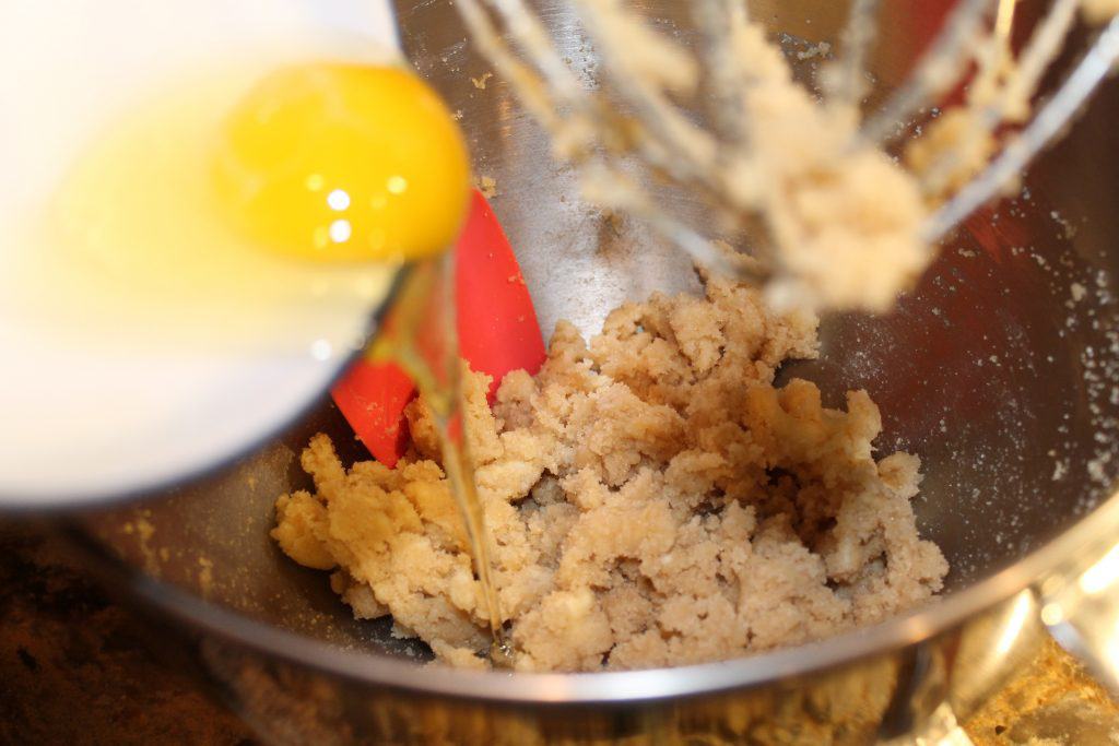 Adding egg to the mixing bowl.