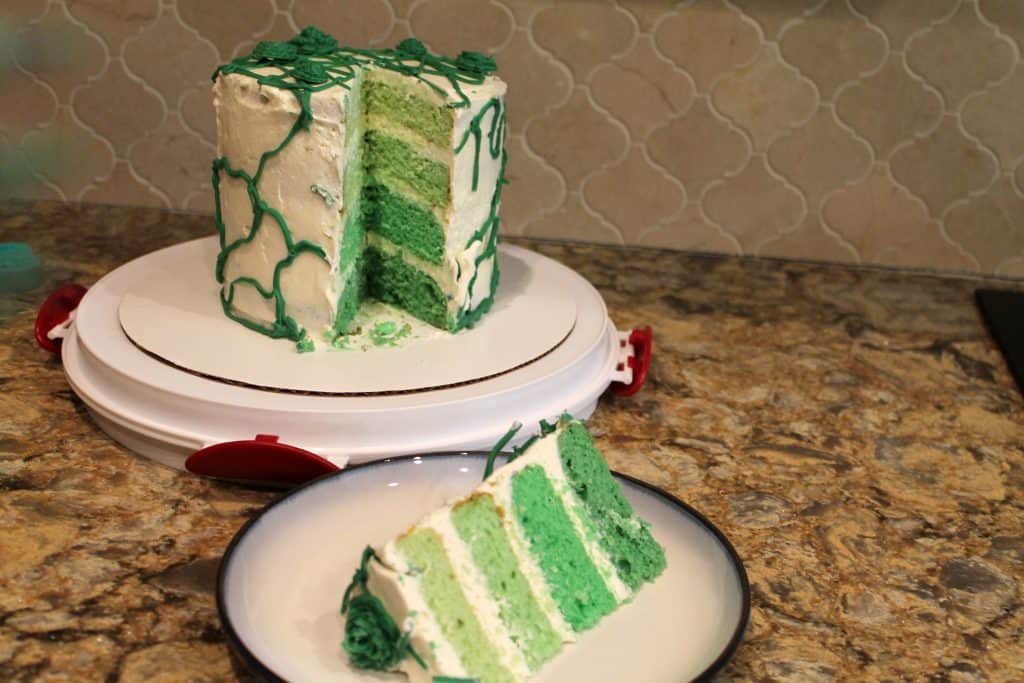 A green ombre cake with a piece sliced out of the whole cake.