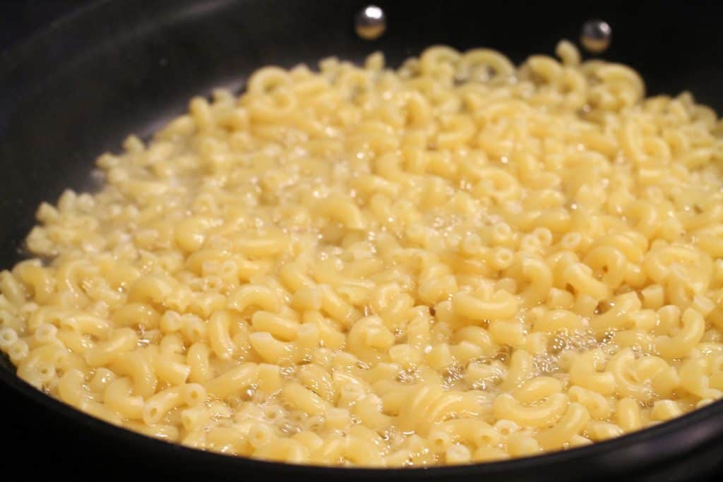 Elbow macaroni noodles being cooked for this recipe.