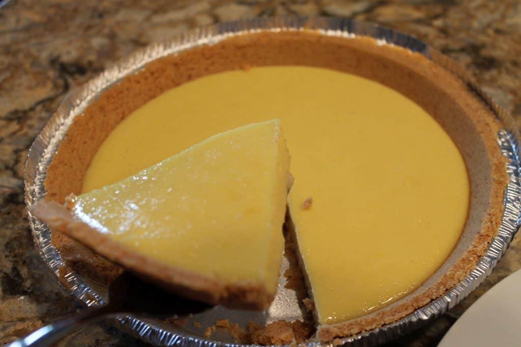 Sour lemon pie slice out of whole pie.