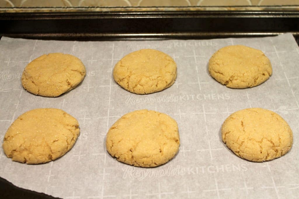 Baked peanut butter cookies on a cookie sheet.