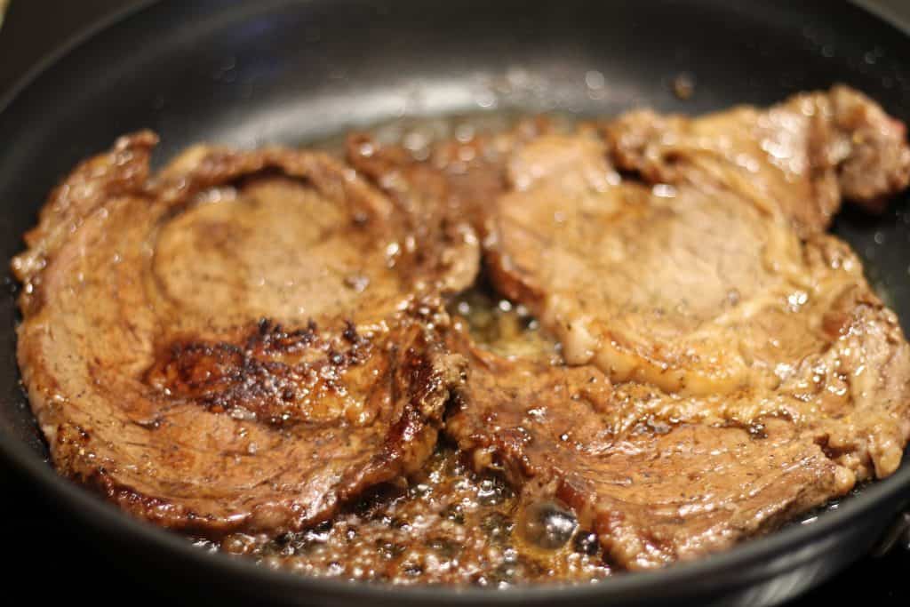 Steak in frying pan cooking