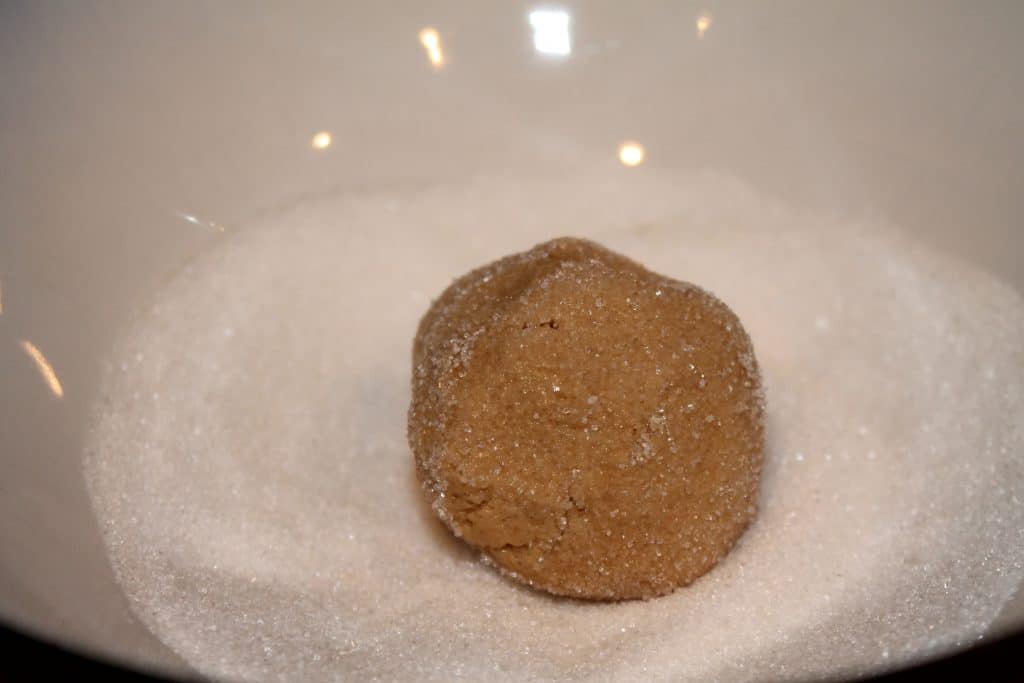 Rolling peanut butter cookie dough balls in sugar.