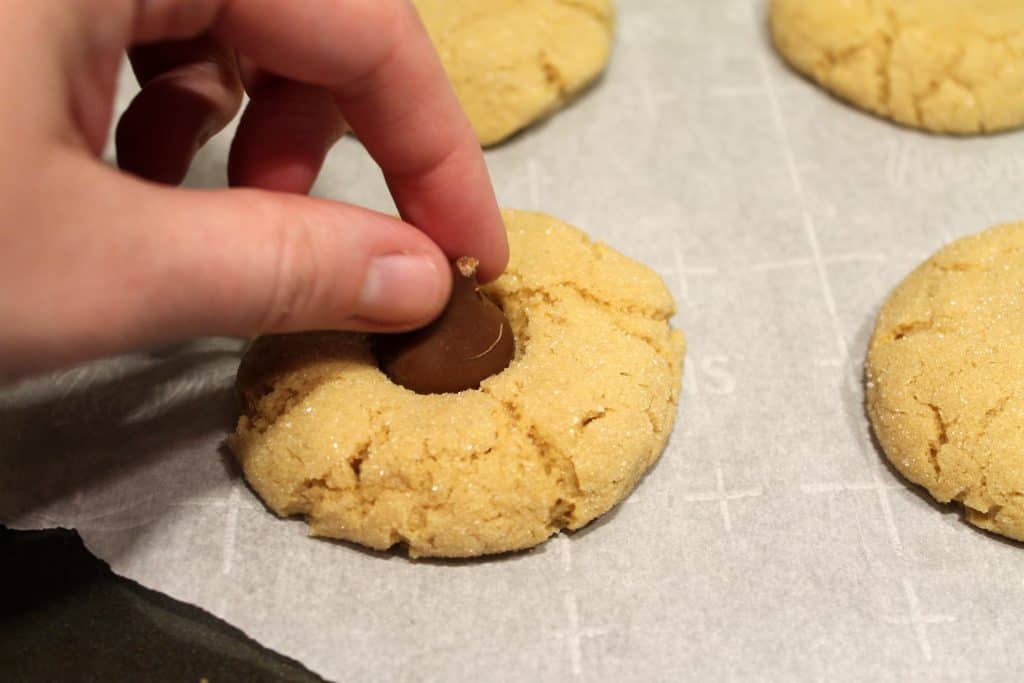 Putting the chocolate kisses in the peanut butter cookies.