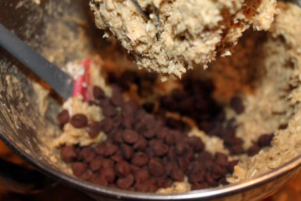 Adding chocolate chips to the oatmeal cookie dough.