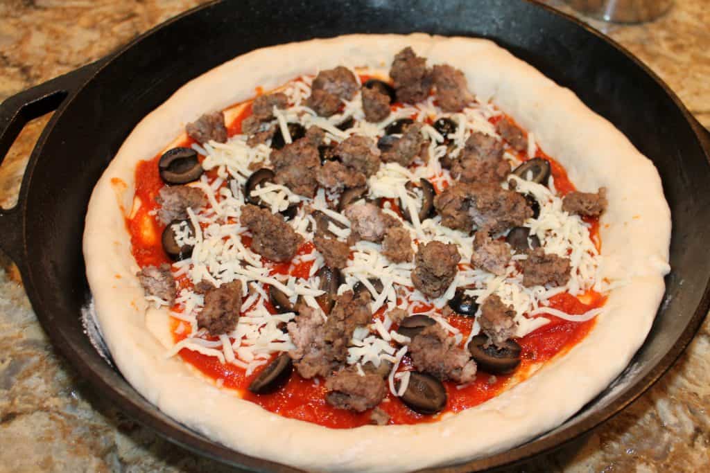 Adding the cheese and hamburger to the pizza