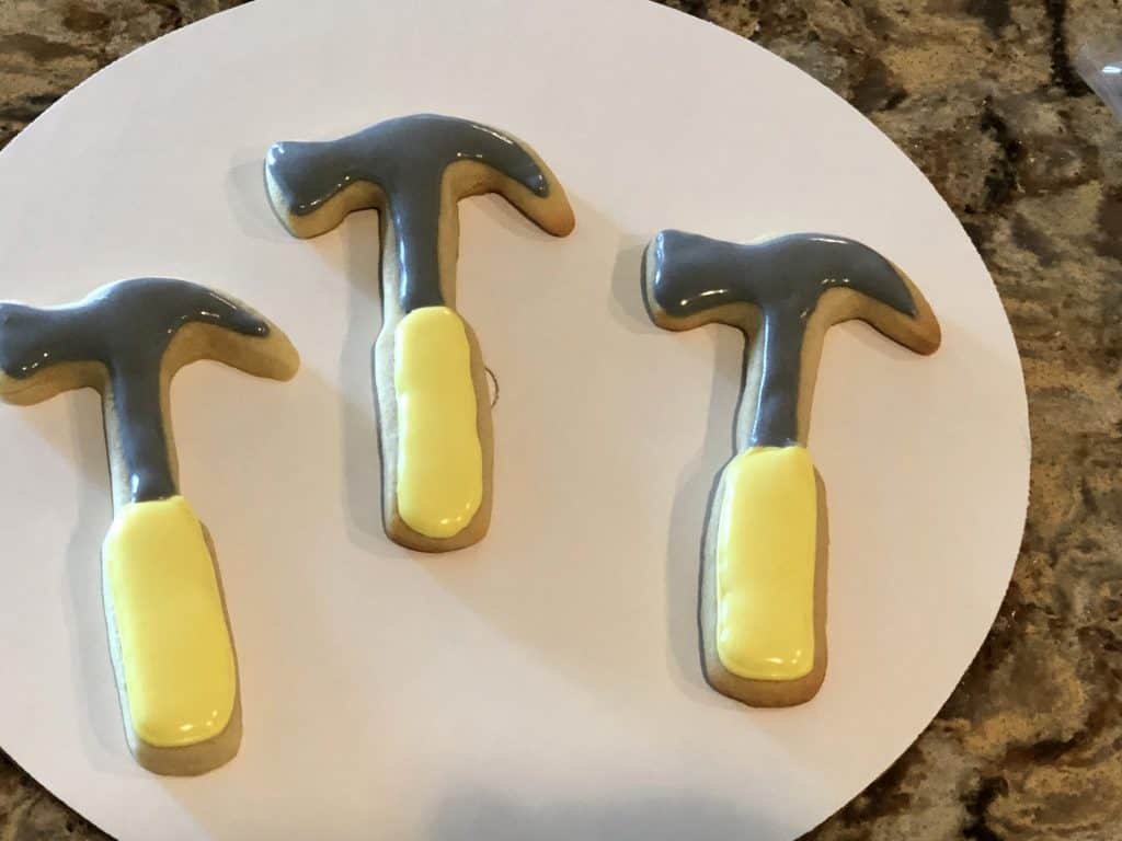 Adding the gray icing to the hammer cookies.