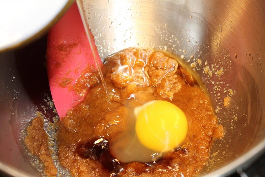 Adding an egg and vanilla extract to the sugar mixture.