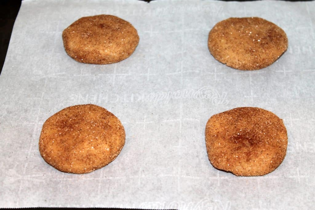 Snickerdoodle cookie balls squashed on cookie sheet